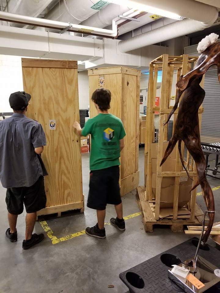 Crew securing a marble koi sculpture with straps outside a casino