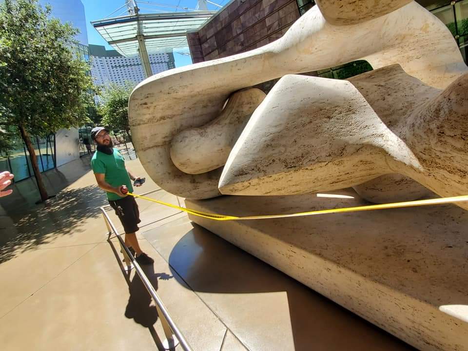 Staff measuring a large-scale outdoor marble sculpture